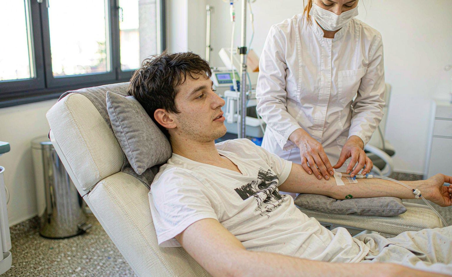 Client receiving a relaxing IV vitamin drip in a bright clinic